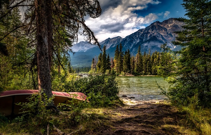 Canoe by a lake with mountains and pine trees