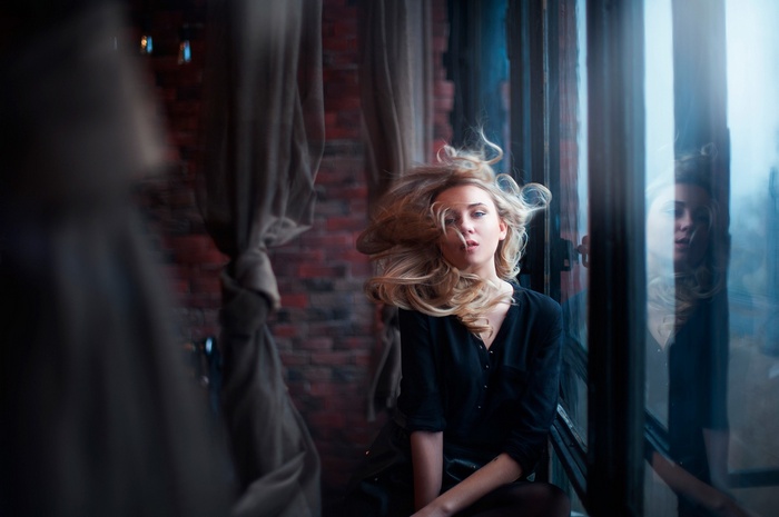 Blonde woman by the window with reflection