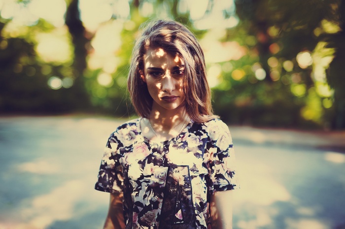 Woman in floral shirt with dappled light on face