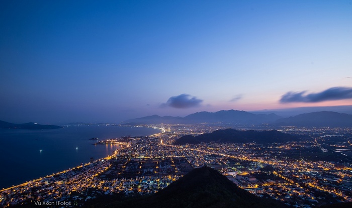 City lights at dusk over a bay and mountains