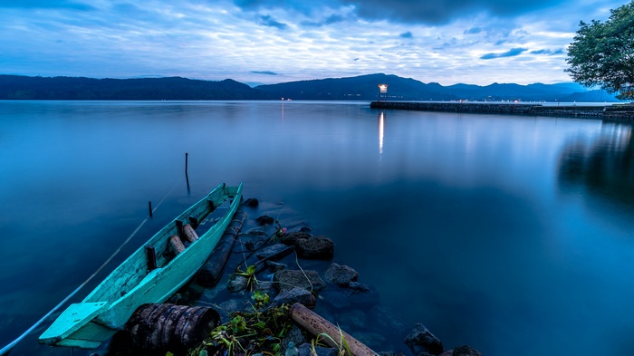 Turquoise boat on a calm lake at dusk in Indonesia