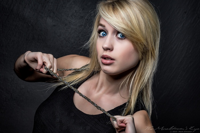 Woman with blonde hair and blue eyes holding a necklace