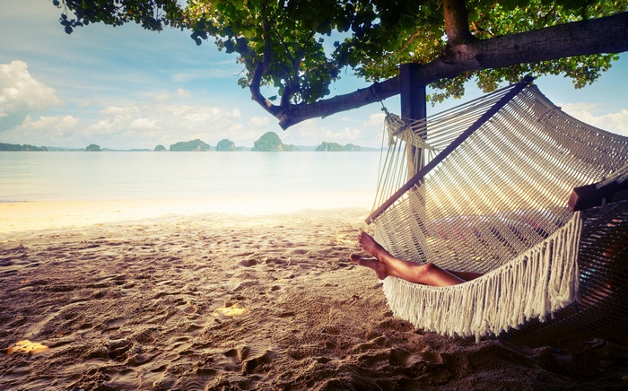 Woman relaxing in a hammock on a tropical beach