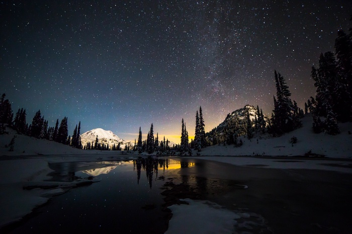 Snowy mountain lake under a starry night sky