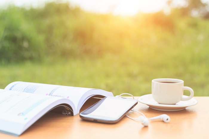 Open book, phone, and coffee cup on a table