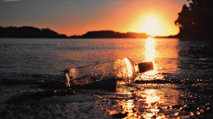 Glass bottle on the shore at sunset