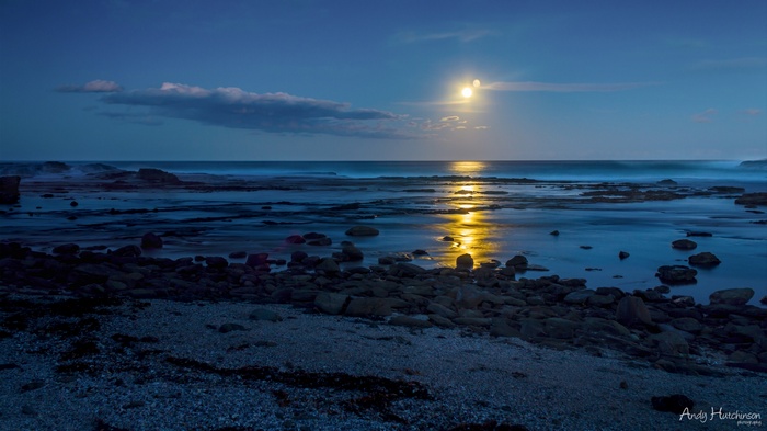 Moonlit beach with rocky shore and ocean waves