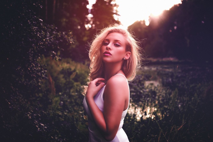 Woman in white dress in a forest at sunset
