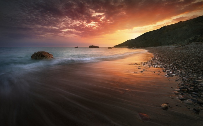 Sunset over a rocky beach in Cyprus with long exposure waves