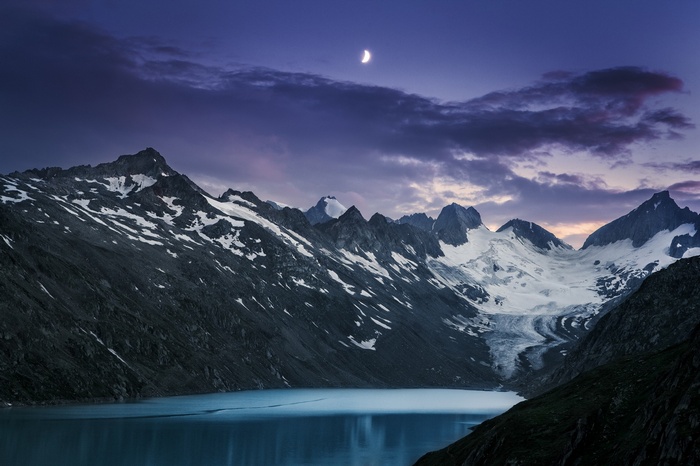 Moonlit mountain range with glaciers and a lake