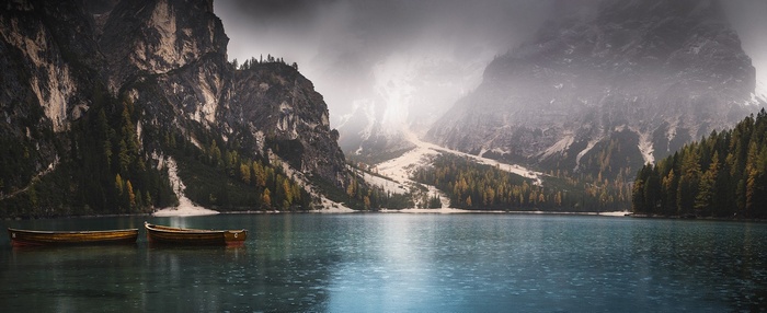 Two wooden boats on a lake in the Alps during a misty rain