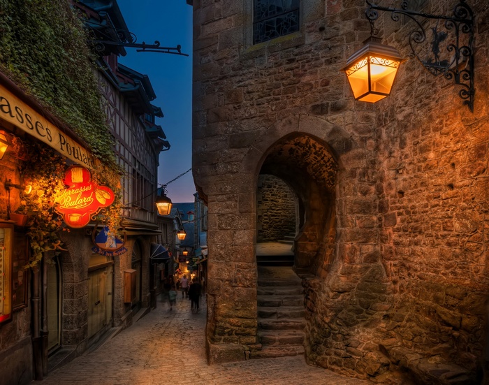 Cobblestone alley with illuminated signs in France