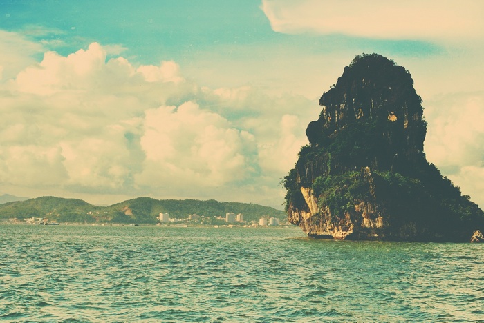 Rock formation in the sea with distant coast and clouds