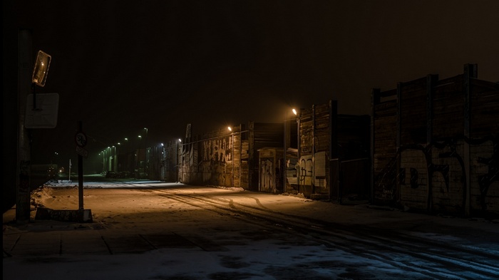 Snowy street at night with industrial buildings and graffiti