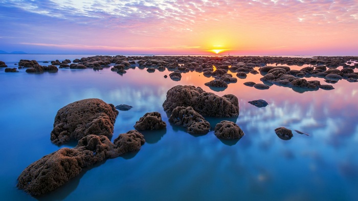 Sunset over the rocky coast with calm water