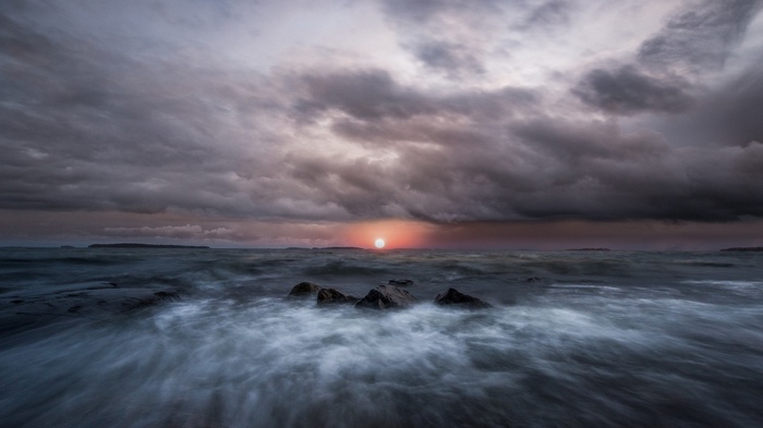 Stormy sunset over the sea with rocks