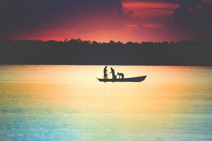 Silhouettes of people in a boat at sunset