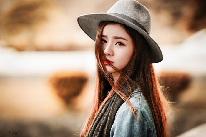 Asian woman with long hair wearing a hat and denim jacket