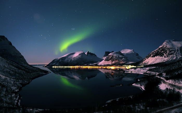 Aurora Borealis over snow-capped mountains and a town