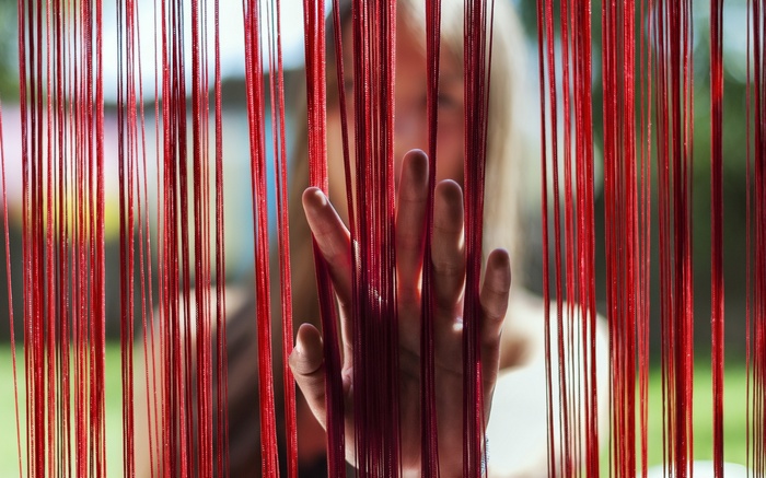 Woman's hand reaching through red strings