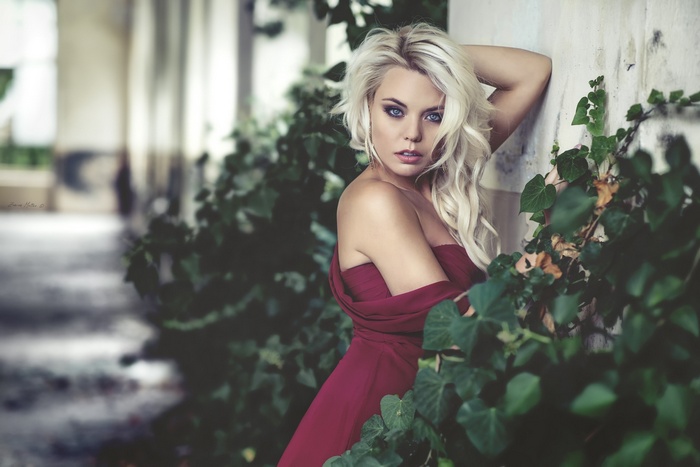 Woman in a red dress leaning against a wall
