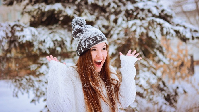 Woman in winter hat and sweater in snow