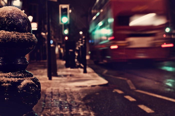 London street at night with a red bus in the snow