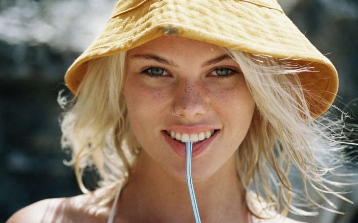 Woman wearing a yellow bucket hat and holding a straw