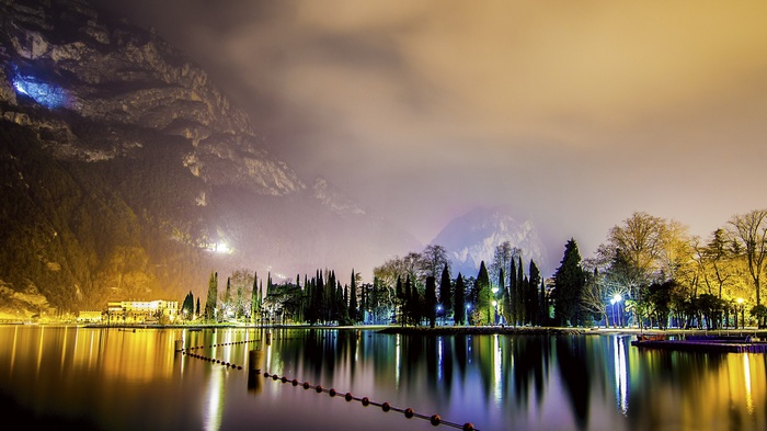 Night landscape with lake, trees, and mountains