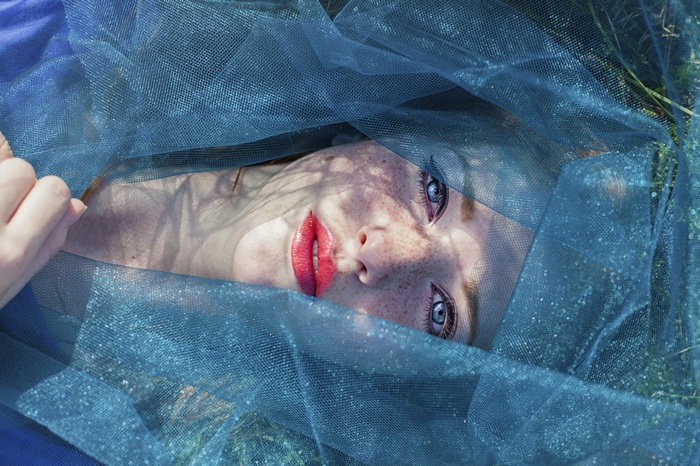 Woman with freckles and blue eyes under blue veil