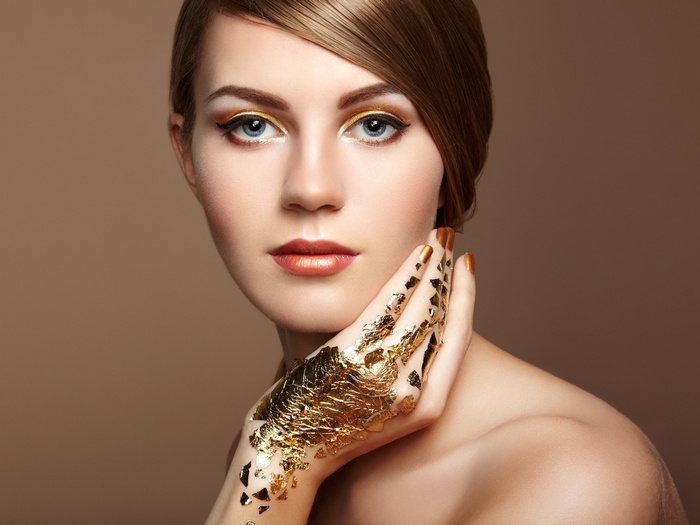 Woman with gold leaf makeup and painted nails