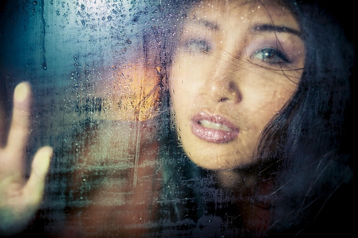 Asian woman with water drops on glass