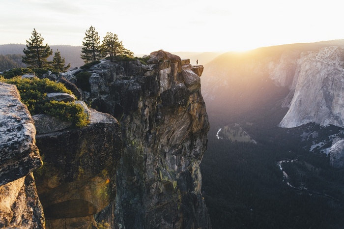 Man standing on cliff edge at Yosemite National Park during sunset