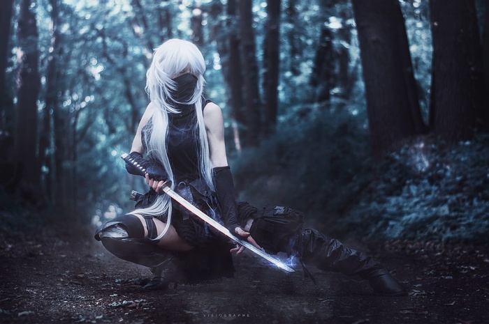 Cosplayer with white hair and sword in forest