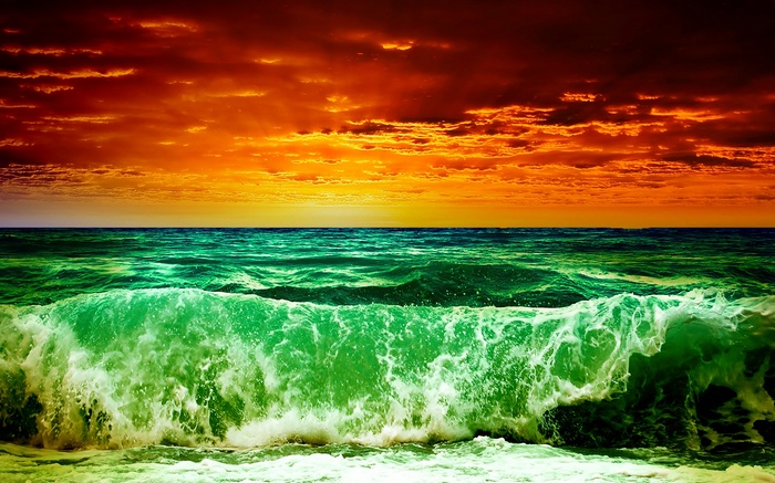 Dramatic sunset over a green ocean wave