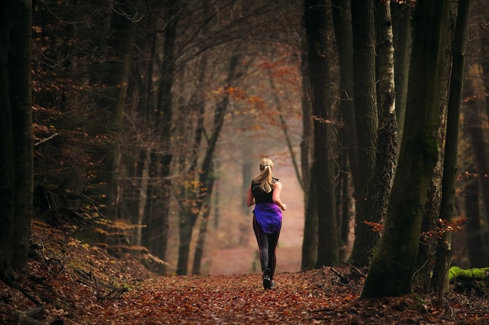 Woman running on a forest path in autumn