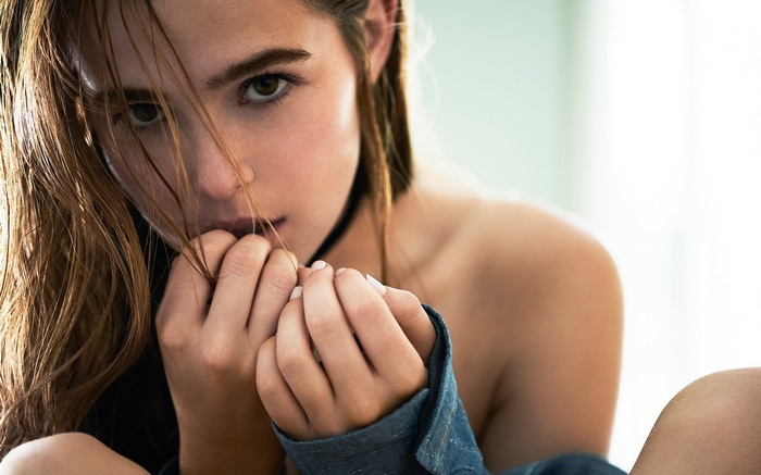 Zoey Deutch with her hands near her face