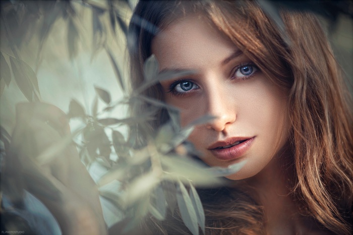 Woman with blue eyes behind leaves