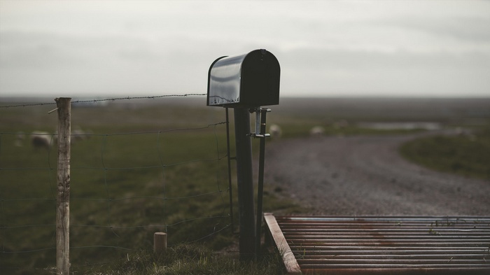 Black mailbox on a rural fence line