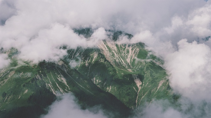 Clouds obscuring a green mountain landscape
