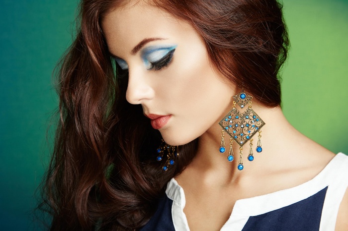 Woman with blue eyeshadow and large earrings