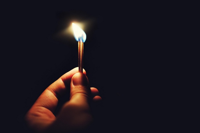 Hand holding burning matches in the dark