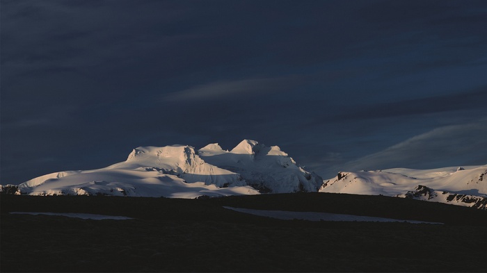 Snow-covered mountains under a dark sky