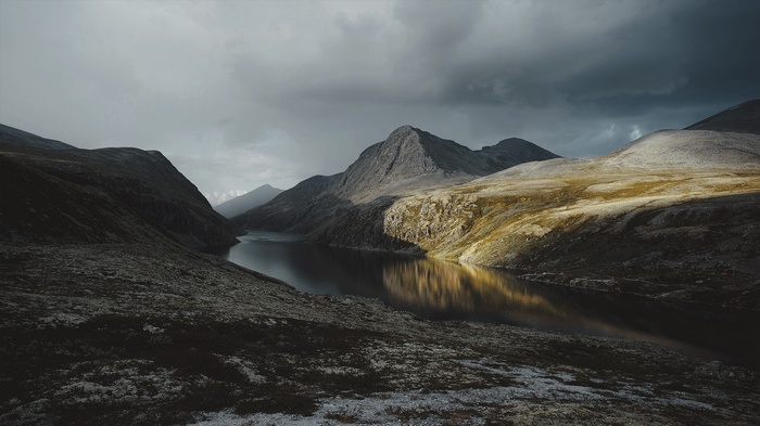 A dramatic mountain lake landscape under stormy skies