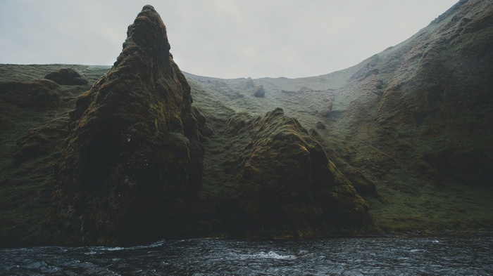 Moss-covered rocks and a river in a misty landscape