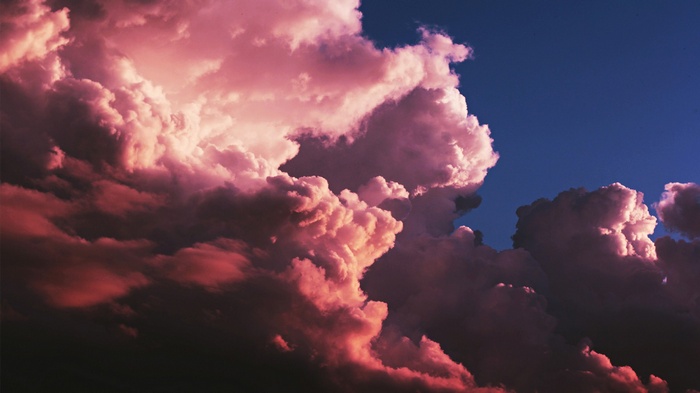 Pink and red clouds against a dark blue sky