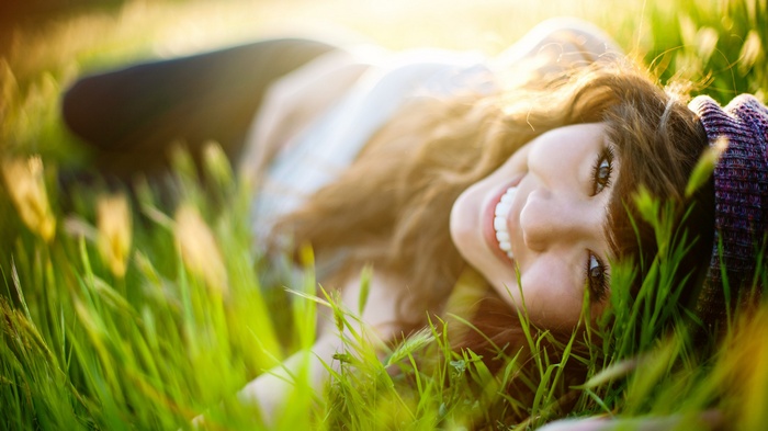 Young woman with brunette hair lying in grass