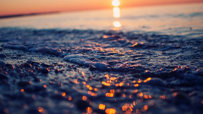 Sunset over the ocean with waves on the shore