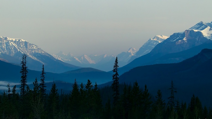 Layered mountains with snow-capped peaks and evergreen trees