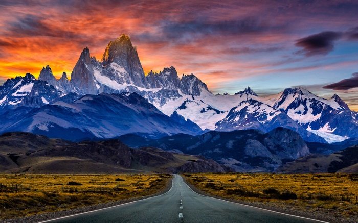 Road leading to snow-capped mountains at sunset